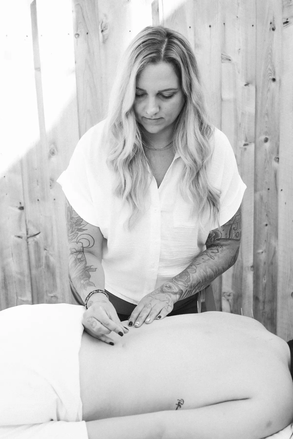 Black-and-white photo of Dr. Sophia Santamaria carefully needling a patient lying on a treatment table